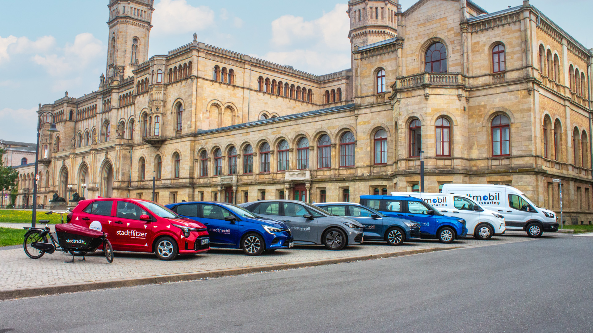 Fahrzeugflotte steht vor Unigebäude